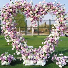 a heart - shaped arrangement of flowers on the grass in front of a tennis court