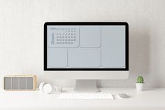 a desktop computer sitting on top of a white desk next to a clock and plant