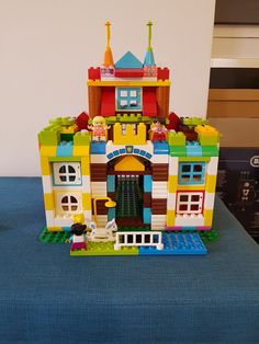 a toy house made out of legos sitting on top of a blue tablecloth