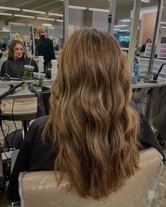 the back of a woman's head as she sits in a chair at a hair salon