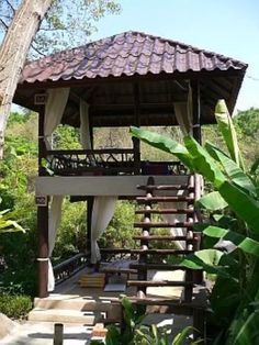 a wooden gazebo sitting in the middle of a lush green forest