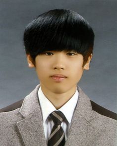 a young man with black hair wearing a gray suit and tie, looking at the camera