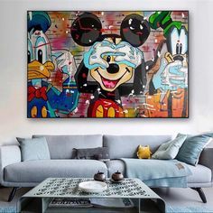 a living room with mickey mouse paintings on the wall and coffee table in front of it