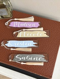 four wooden name tags sitting on top of a brown leather case next to a bottle