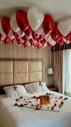 red and white balloons are hanging from the ceiling above a bed