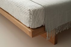 a bed with a wooden frame and striped blanket