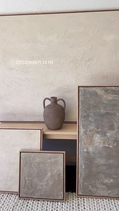 a vase sitting on top of a wooden table next to four framed pictures in front of a wall