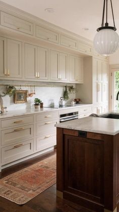 a kitchen with white cabinets and an island in the middle of the room is lit by a pendant light