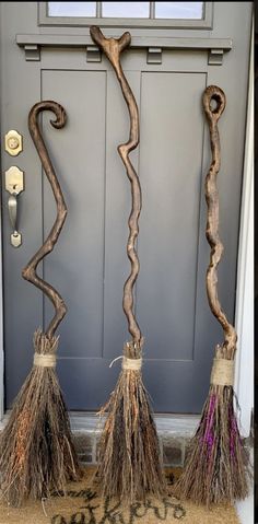 two brooms sitting next to each other in front of a door