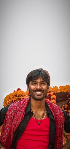 a man in red shirt and black vest posing for the camera with food piled on top of him