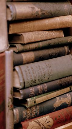 a stack of old books sitting on top of a wooden shelf next to each other