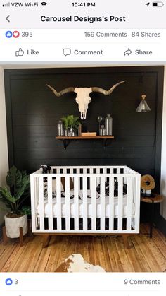 a white crib in front of a black wall and cow skull on the wall