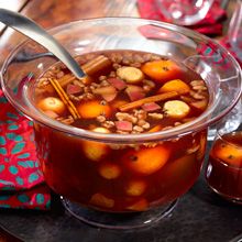 a glass bowl filled with soup sitting on top of a table next to two glasses