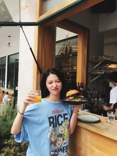 a woman holding up a plate with food on it in front of a restaurant window