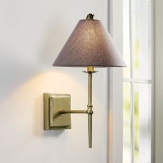 a wall lamp with a shade on it next to a window in a white room