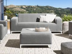 a couch and ottoman on a patio with mountains in the background