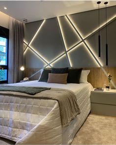 a large bed sitting in a bedroom next to a window with lights on the headboard