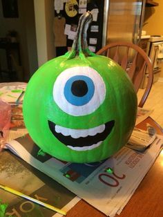 a green pumpkin with an evil face painted on it's side sitting on top of a table