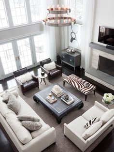 a living room with couches, chairs and a fire place in the center area