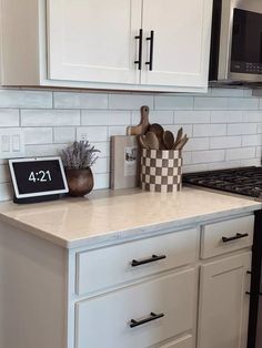 a kitchen counter with white cabinets and black appliances in the back drop off cabinetry