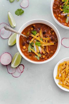 three bowls of chili and cheese soup with sliced radishes, cilantro, and lime wedges