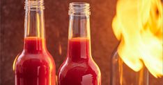 two bottles filled with red liquid next to a fire