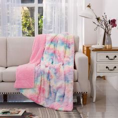 a living room with a white couch and a pink blanket on top of the couch