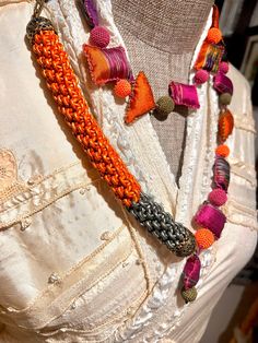 an orange and pink beaded necklace on a mannequin's neckline