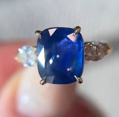 a close up view of a ring with a blue stone and two diamonds on it