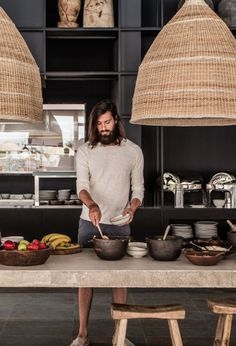 a man standing in front of a table filled with pots and pans on top of it