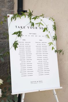 a wedding seating sign with greenery on it