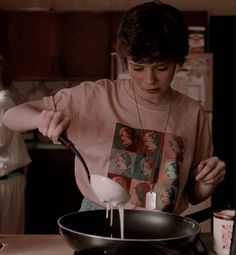 a young man is stirring something in a frying pan