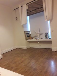 an empty room with wooden floors and white curtains