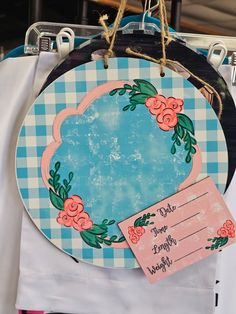 a blue and white checkered table cloth with a round sign hanging from it's side