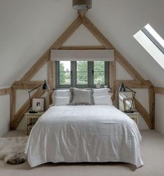 an attic bedroom with white bedding and wooden beams