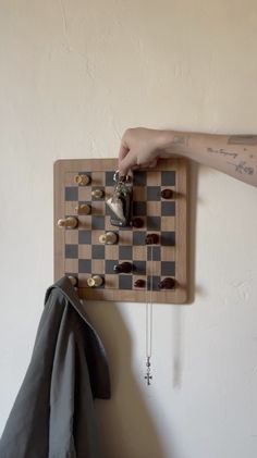 a person playing chess on a wooden board with other items hanging from the wall behind it