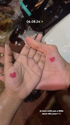 two hands with small red hearts on their palms in front of a sink that has water running down it