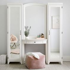 a white dressing table with mirror and stool in the corner next to a pink bean bag