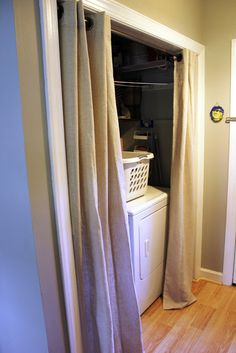 a washer and dryer are in the corner of this room with curtains open