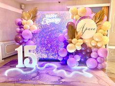 a purple and white balloon arch with the number fifteen on it in front of a backdrop