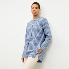 Our stylists recommend sizing down one size in the Nichols top. This modern take on the classic button-up is made from crisp Italian cotton and features a stand collar and center bib. Side slits and a long, relaxed fit make for a tunic-style silhouette that’s balanced by slim sleeves. Wide cuffs allow you to roll up your sleeves with ease, while a pleat at the back shoulder seam creates a clean line down the back. Wear the Nichols over a pair of slim-fitting pants to balance the easy fit. Made i Spring Tops With Placket For Daywear, Spring Placket Top For Daywear, Classic Spring Tops With Placket, Fitting Pants, Womens History Month, Work Style, Tunic Style, Wide Cuff, A Stand