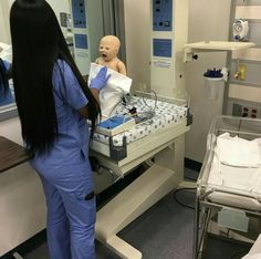 a woman in scrubs standing next to a dummy