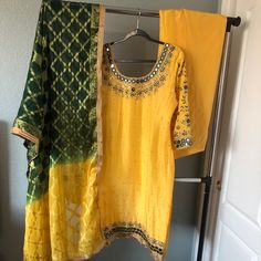 It’s A Yellow Top With Mirror/ Stone Embroidery Top With Full Work On Sleeves. Comes With Matching Yellow Salwar, And Ombr Emerald Green/ Yellow Chunni. Brand New. Estimated Measurements: Suit- Bust 40, Waist 42, Length 42 Salwar Length: 43. Margins 2 1/2’ Each Side Outfits Will Not Fit Into A Standard Size Category, All Of The Outfits Are Custom Made. *Most Outfits Are Pre Worn Unless Stated. Worn Items Will Show A Few Signs Of Wear Including Minor Stains, Missing Stones Around The Heavy Pieces Yellow Silk Set For Summer, Yellow Kurta With Mirror Work For Party, Festive Yellow Salwar Kameez With Mirror Work, Yellow Mirror Work Kurta For Party, Elegant Yellow Traditional Wear With Gota Work, Hand Embroidery Suits Punjabi Party Wear, Yellow Salwar Kameez With Gold Embroidery For Eid, Yellow Salwar Kameez With Mirror Work For Party, Elegant Yellow Salwar Kameez With Dabka Work