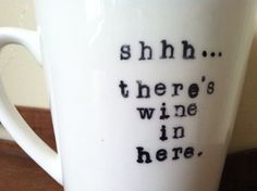 a white coffee cup with black writing on it that says, shh there's wine in here