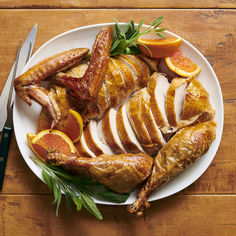 a white plate topped with sliced up turkey and oranges on top of a wooden table