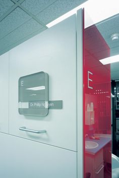 an office cubicle with a red and white door on the wall next to a sink