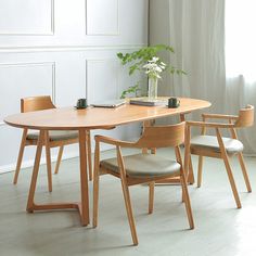 a wooden table with four chairs around it and a plant in the middle on top