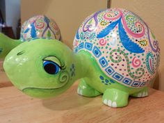 two ceramic turtle figurines sitting on top of a wooden table next to each other