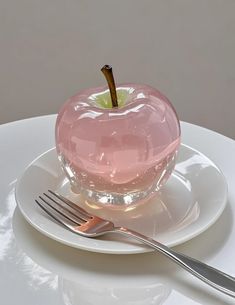 an apple shaped dessert sitting on top of a white plate next to a knife and fork