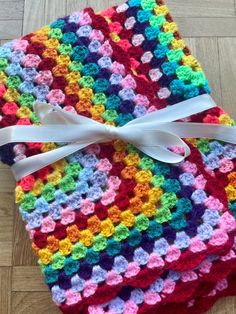 two crocheted squares with white ribbon on them sitting on the floor next to each other